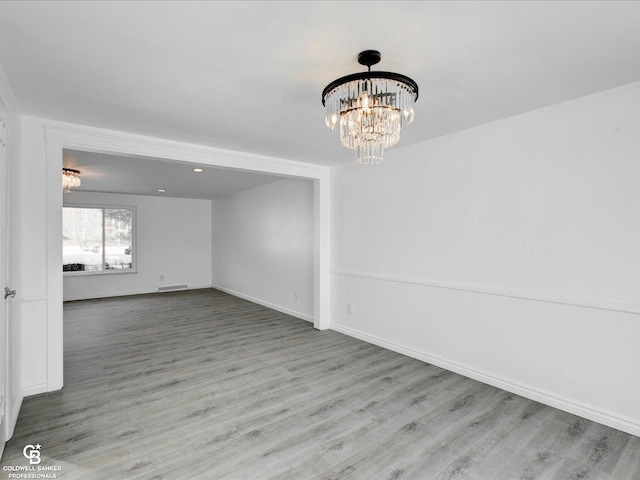 empty room featuring a chandelier and light wood-type flooring