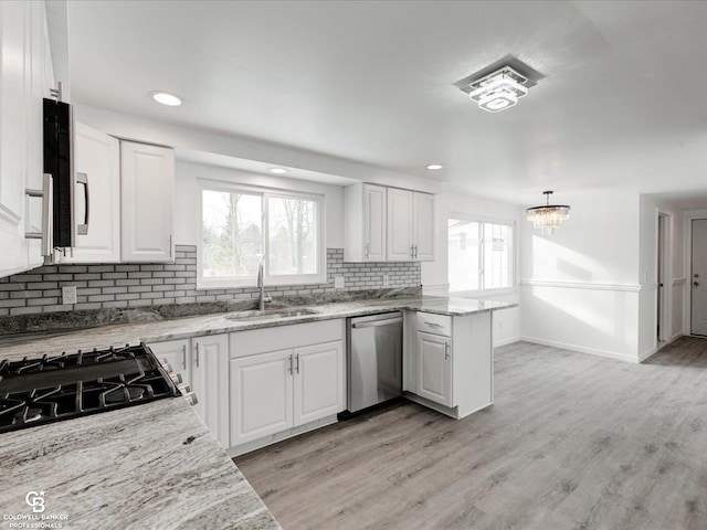 kitchen with dishwasher, light stone countertops, sink, and white cabinets