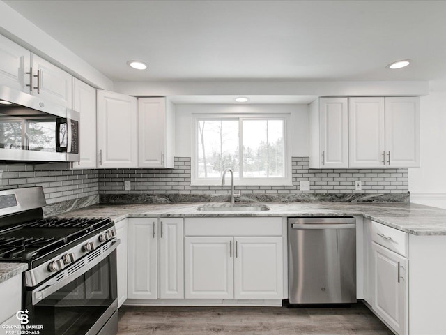 kitchen with light stone counters, sink, stainless steel appliances, and white cabinets