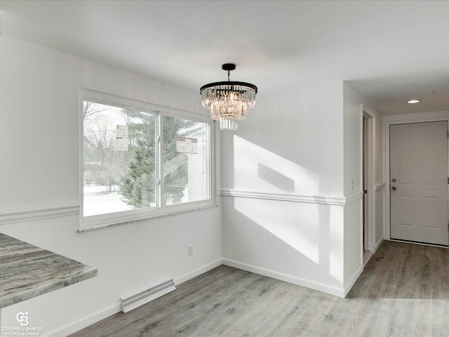 unfurnished dining area with a chandelier, light wood-type flooring, and a baseboard heating unit