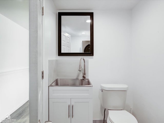 bathroom featuring wood-type flooring, toilet, washer / clothes dryer, and vanity