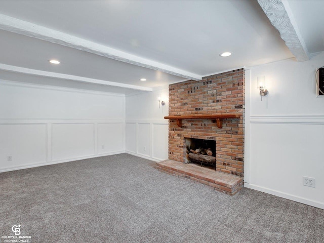 unfurnished living room with a fireplace, beamed ceiling, and carpet flooring