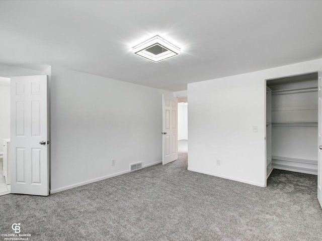 unfurnished bedroom featuring a walk in closet, a closet, and carpet