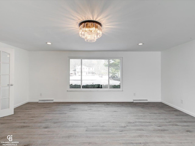 spare room with light hardwood / wood-style flooring and a notable chandelier