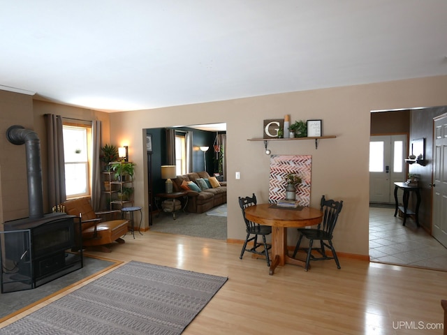 dining room featuring a wealth of natural light, light wood-type flooring, and a wood stove