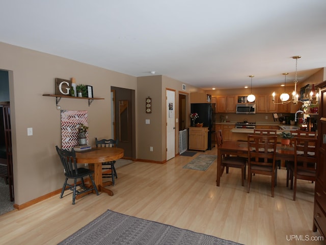 dining area with an inviting chandelier, sink, and light wood-type flooring