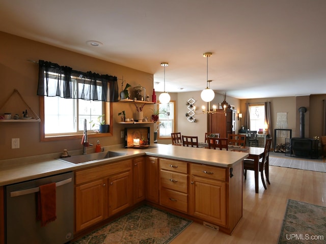 kitchen with sink, hanging light fixtures, a wealth of natural light, stainless steel dishwasher, and kitchen peninsula