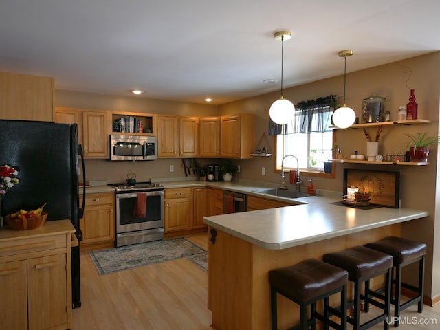 kitchen featuring appliances with stainless steel finishes, sink, a kitchen bar, hanging light fixtures, and kitchen peninsula