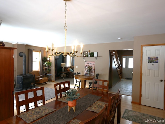 dining space featuring an inviting chandelier, wood-type flooring, and a wood stove