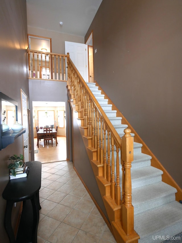 stairway with tile patterned flooring and a high ceiling