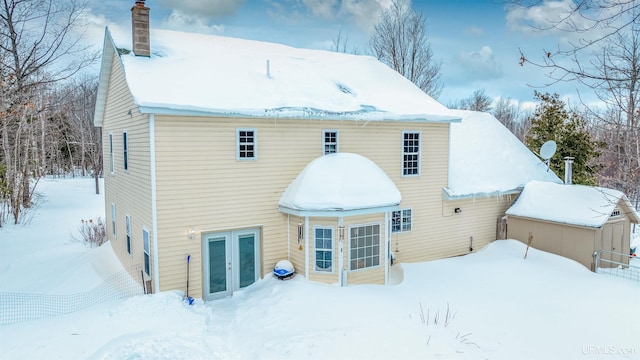 snow covered rear of property featuring french doors