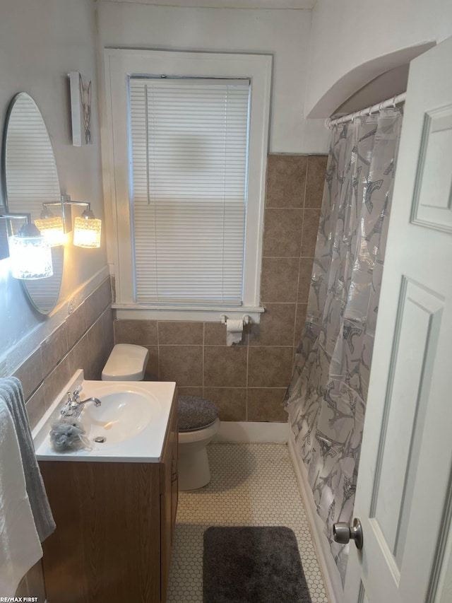 bathroom featuring tile patterned floors, vanity, toilet, and tile walls