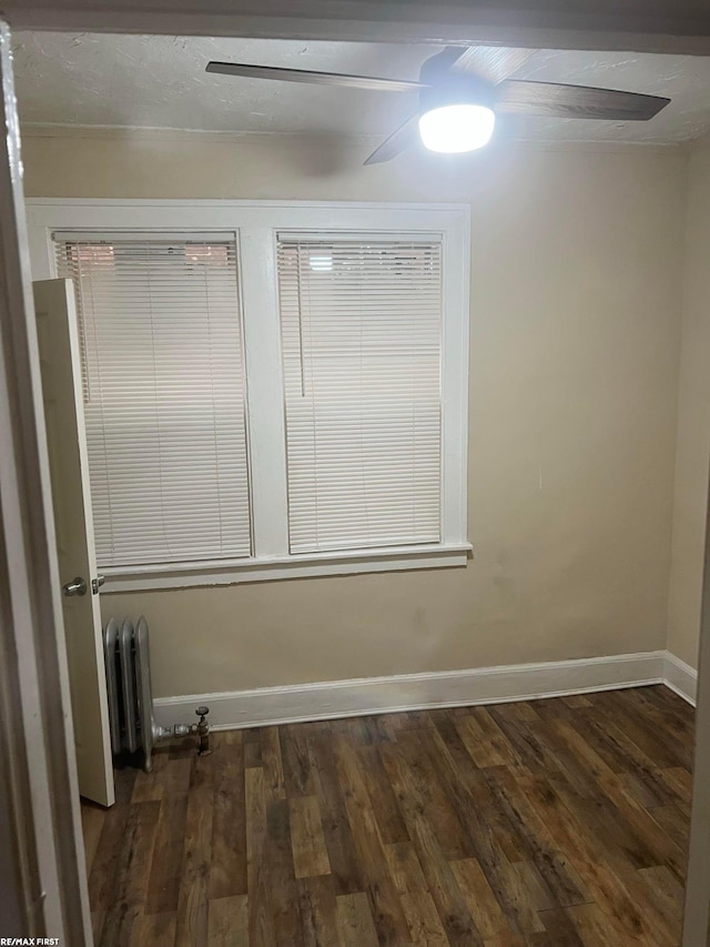 unfurnished room featuring ceiling fan, radiator heating unit, and dark hardwood / wood-style flooring