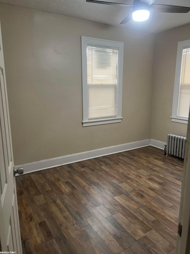 empty room featuring ceiling fan, radiator heating unit, and dark hardwood / wood-style flooring