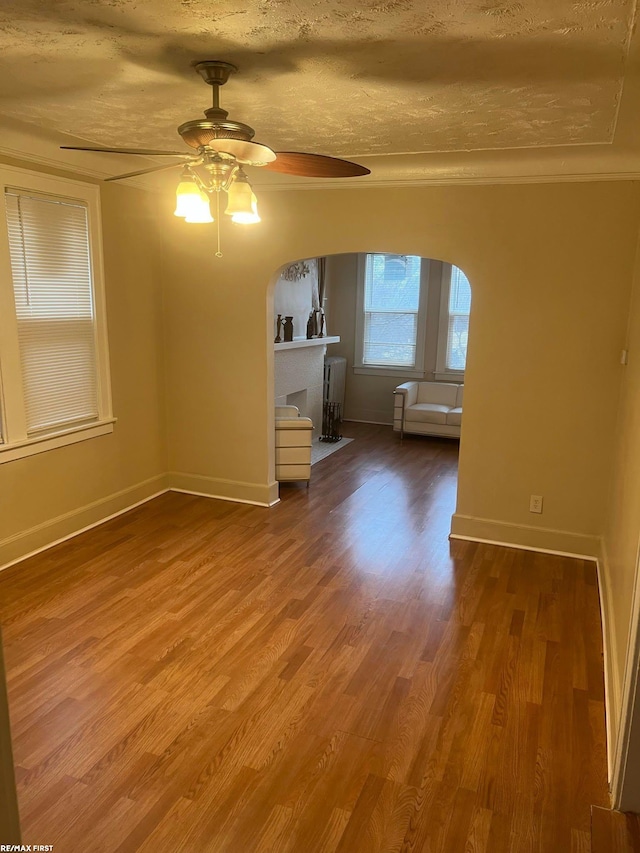 unfurnished room with crown molding, ceiling fan, hardwood / wood-style flooring, and a textured ceiling