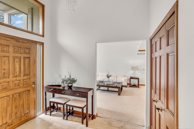 foyer entrance featuring a high ceiling and light carpet