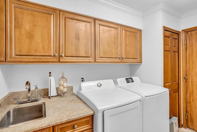 clothes washing area featuring cabinets, washing machine and dryer, sink, and ornamental molding