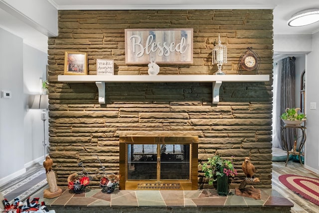 interior details with crown molding, a stone fireplace, and hardwood / wood-style flooring