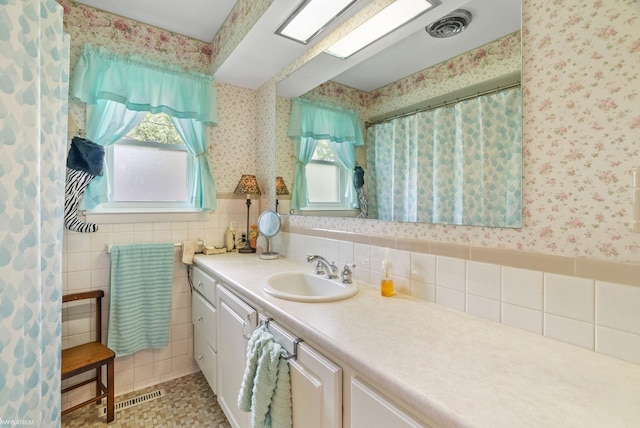 bathroom with a shower with curtain, vanity, and tile walls