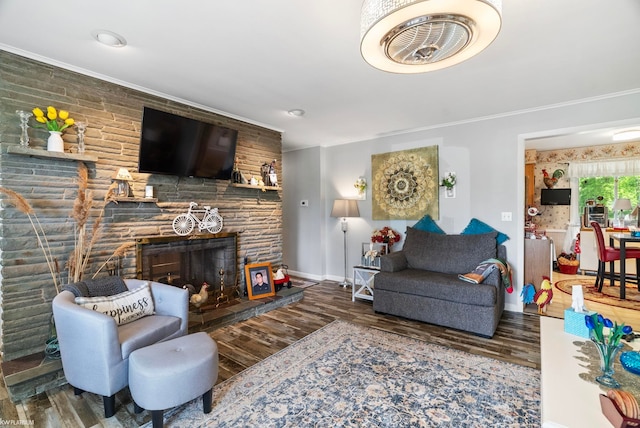 living room featuring wood-type flooring, a stone fireplace, and crown molding