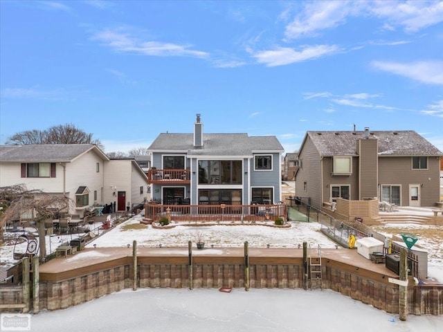 snow covered property with a deck, fence private yard, and a chimney