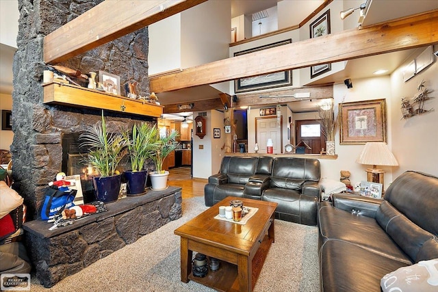 living area with a stone fireplace and a high ceiling