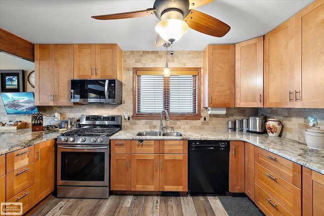 kitchen featuring light stone counters, wood finished floors, a sink, decorative backsplash, and appliances with stainless steel finishes