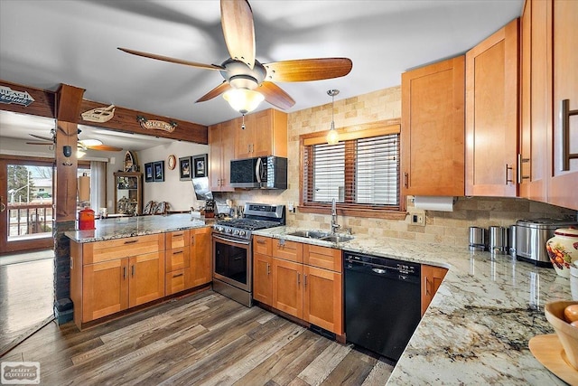 kitchen with dark wood finished floors, a peninsula, a sink, black appliances, and a wealth of natural light