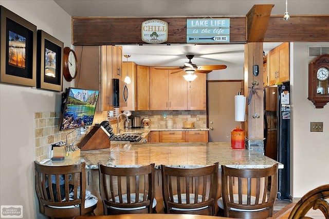 kitchen with stainless steel microwave, tasteful backsplash, and a peninsula