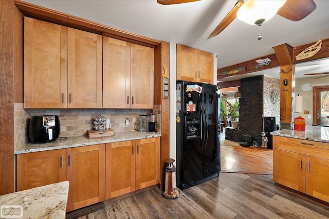 kitchen with black fridge with ice dispenser, light stone countertops, ceiling fan, and dark wood-style flooring