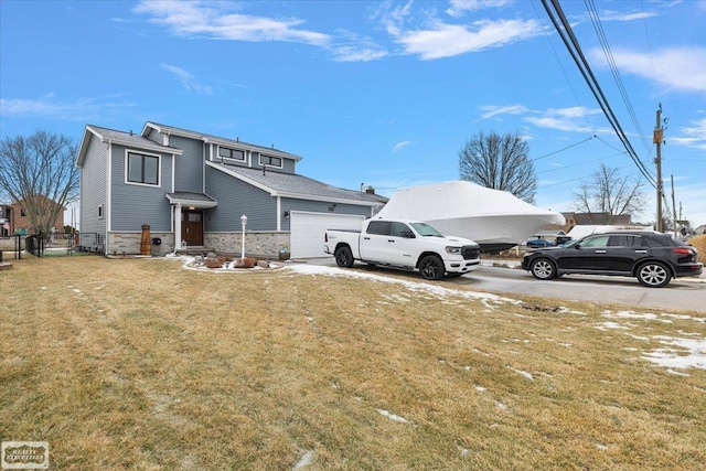 exterior space with stone siding, a front lawn, an attached garage, and fence