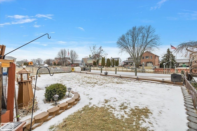 snowy yard featuring fence and a residential view