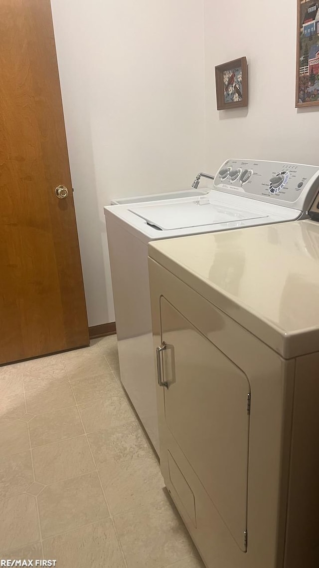 laundry room with independent washer and dryer and light tile patterned floors