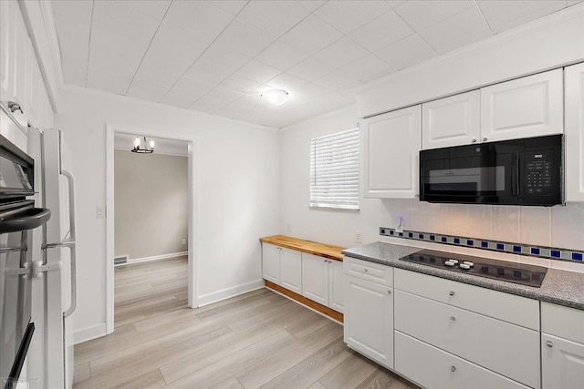 kitchen with tasteful backsplash, white cabinets, light hardwood / wood-style floors, black appliances, and crown molding