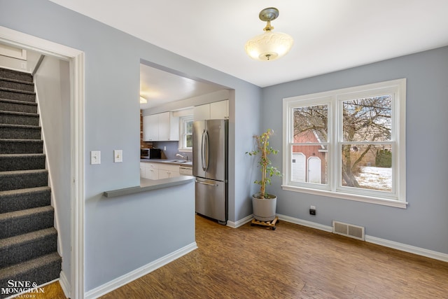 kitchen featuring pendant lighting, white cabinets, stainless steel refrigerator, and light hardwood / wood-style flooring