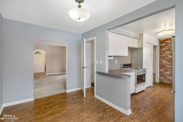 kitchen featuring dark wood-type flooring, stainless steel gas range, fridge, and white cabinets