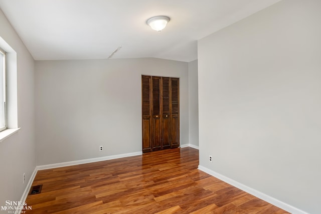 unfurnished room featuring hardwood / wood-style flooring and vaulted ceiling