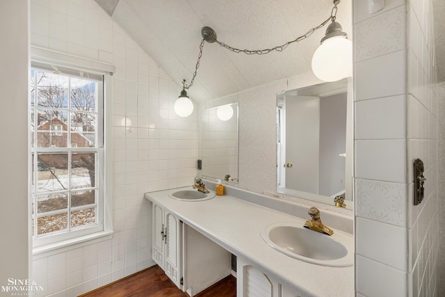 bathroom featuring tile walls, vanity, vaulted ceiling, and wood-type flooring