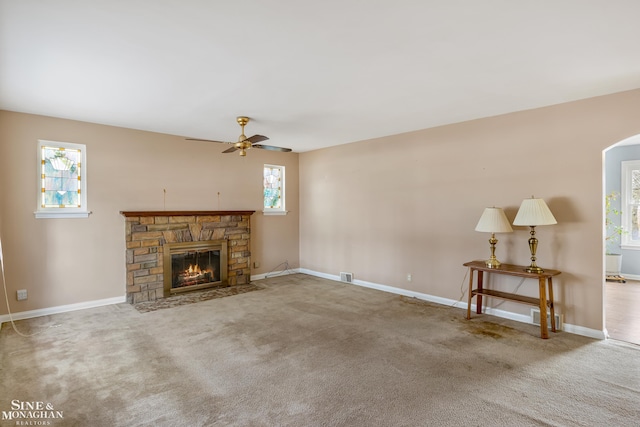 living room featuring a stone fireplace, ceiling fan, and carpet