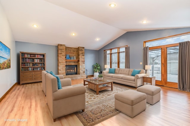 living room featuring a fireplace, light hardwood / wood-style floors, and vaulted ceiling