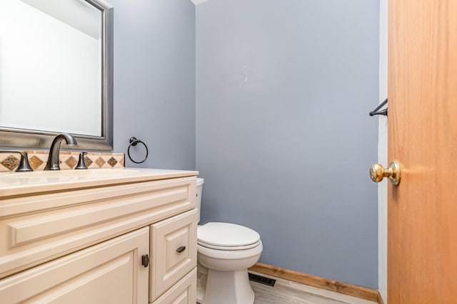 bathroom featuring vanity, backsplash, hardwood / wood-style flooring, and toilet