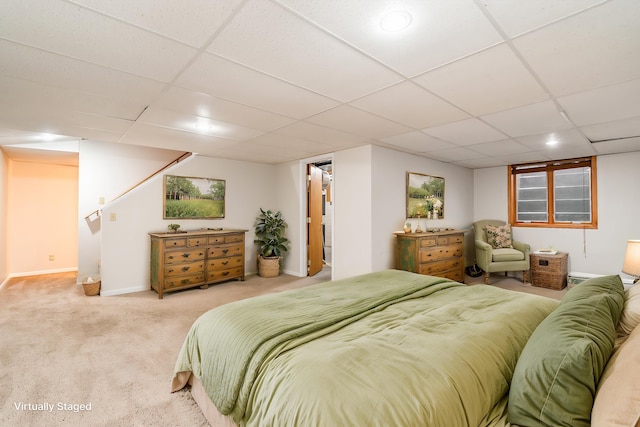 bedroom featuring light carpet and a drop ceiling