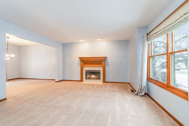 unfurnished living room featuring light colored carpet and a chandelier