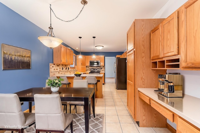 kitchen with stainless steel appliances, tasteful backsplash, pendant lighting, and light tile patterned floors