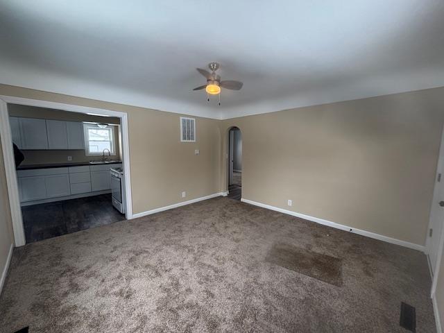 unfurnished bedroom featuring dark colored carpet, sink, and ceiling fan