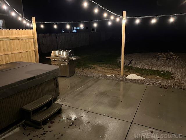 patio at twilight featuring a hot tub