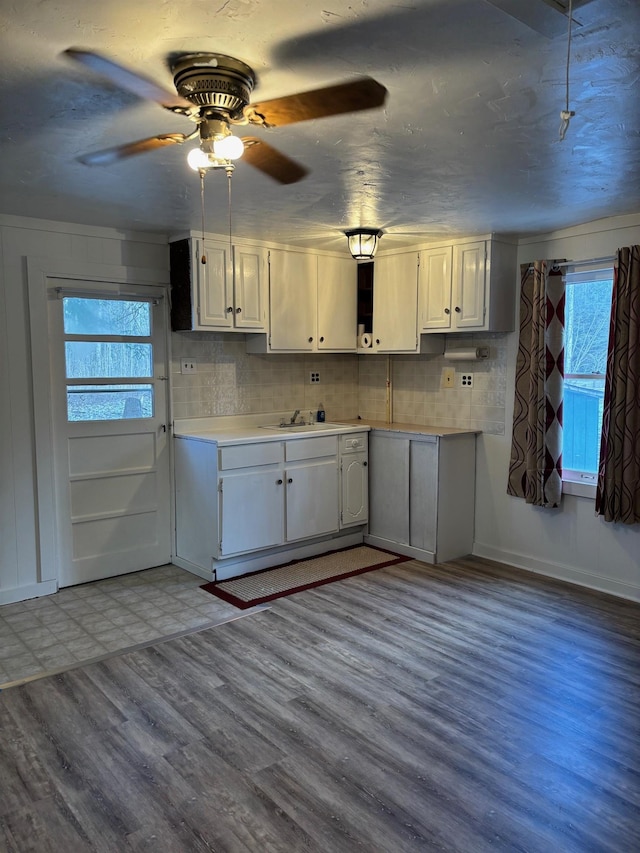 kitchen with tasteful backsplash, sink, light wood-type flooring, and white cabinets