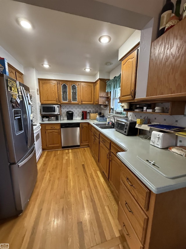 kitchen featuring appliances with stainless steel finishes, sink, light hardwood / wood-style floors, and decorative backsplash