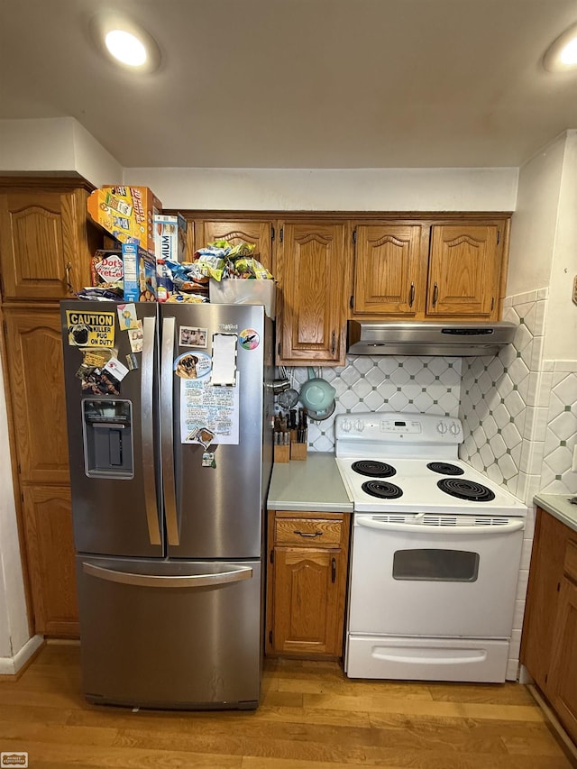 kitchen featuring decorative backsplash, white electric range, stainless steel fridge, and light hardwood / wood-style flooring