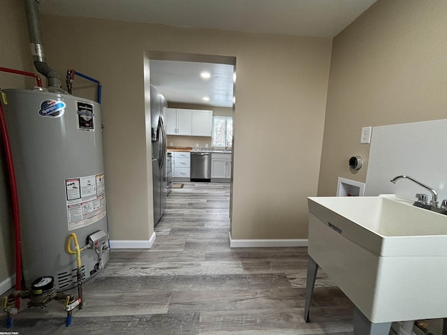 laundry area with sink, light wood-type flooring, and gas water heater